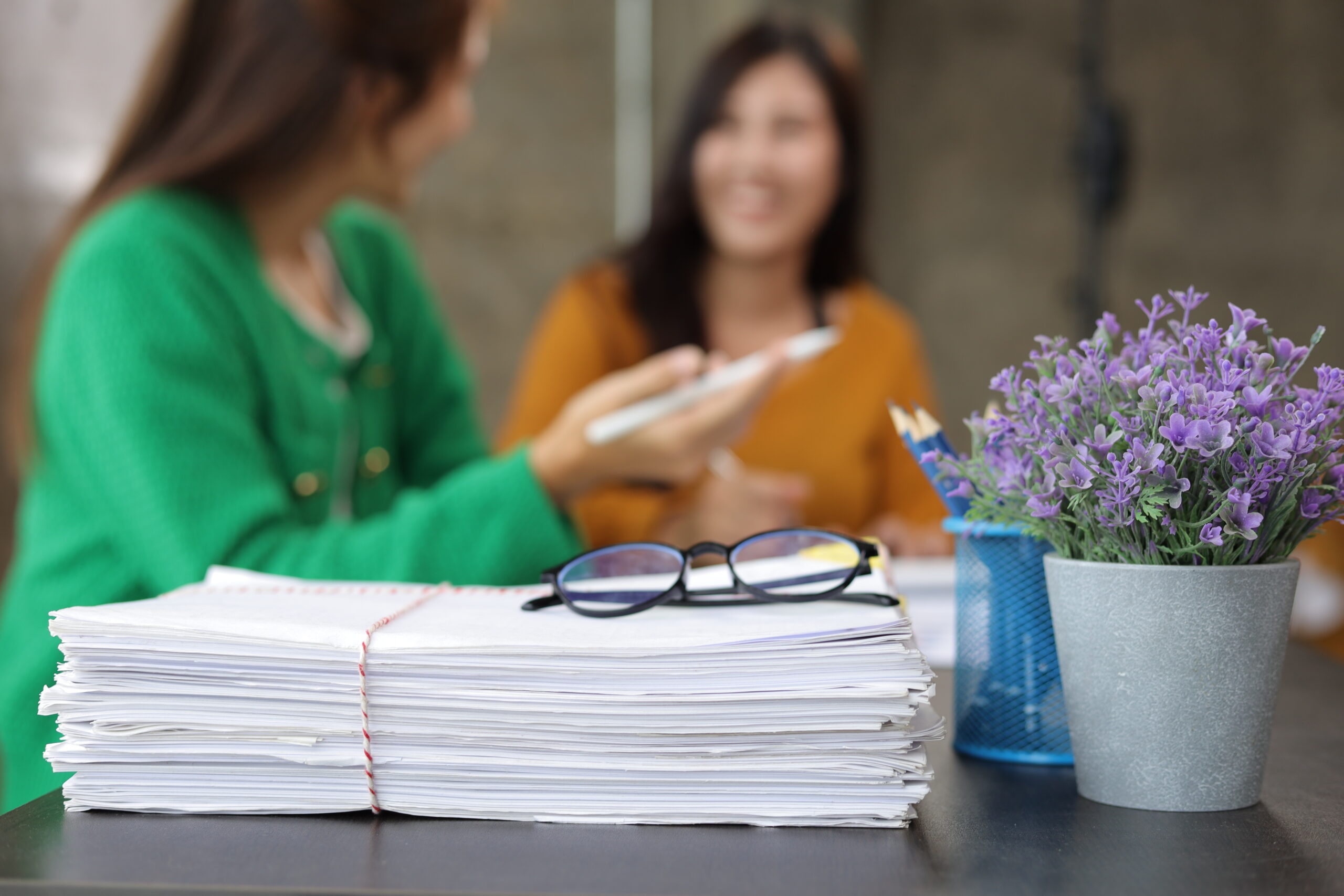 Kolleginnen diskutieren Papierkram im Büro.